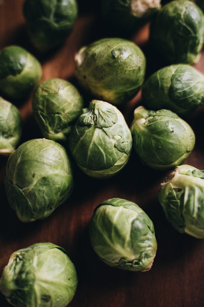Close-up view of fresh Brussels sprouts scattered on a wooden surface. Ideal for healthy eating concepts.